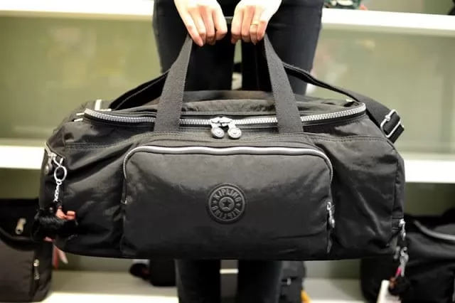 mãos segurando uma mala de viagem preta simbolizando alguém fazendo uma viagem para bonito