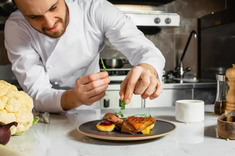 Chefe De Cozinha finalizando prato a base de carne de jacaré